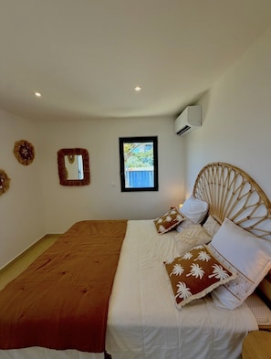 Un dormitorio con una cama, una ventana, un equipo de aire acondicionado y decoración en la pared.