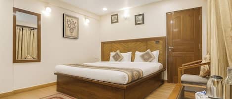 A hotel room with a wooden bed, a small table with a tray, a mirror, and a door.