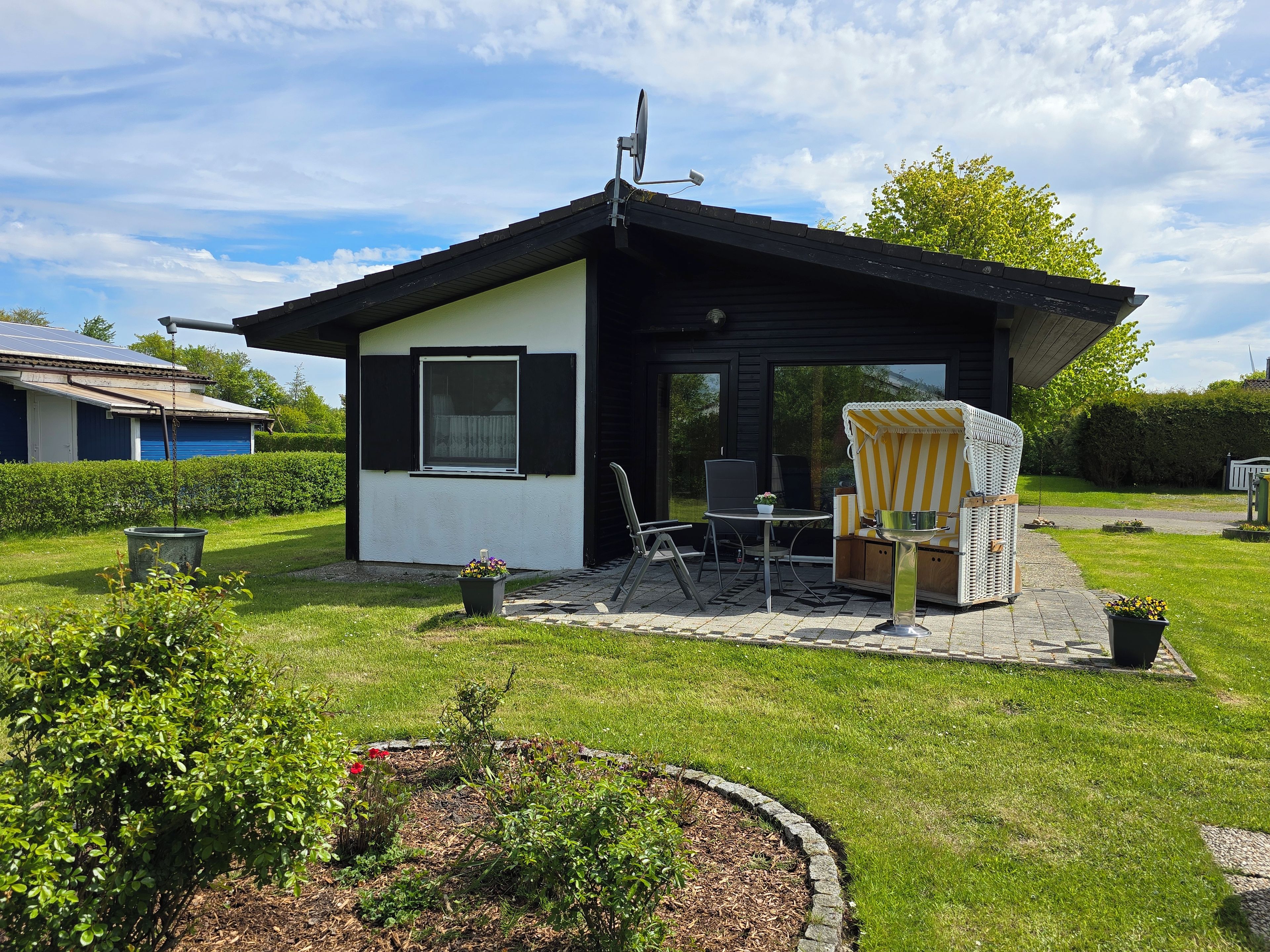 Une petite maison avec un patio, une chaise et une table.