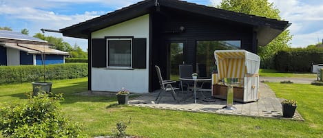 Una casita con un patio, una silla y una mesa.