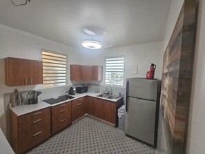 A compact kitchen with wooden cabinets, a built-in sink, and a refrigerator. - Cozy 1-bedroom apartment in beautiful San Juan with AC (San Juan)