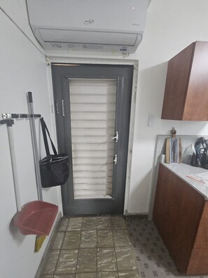 A narrow hallway with a closed door, a small bench, a wall-mounted rack, and a cabinet with a mirror. - Cozy 1-bedroom apartment in beautiful San Juan with AC (San Juan)