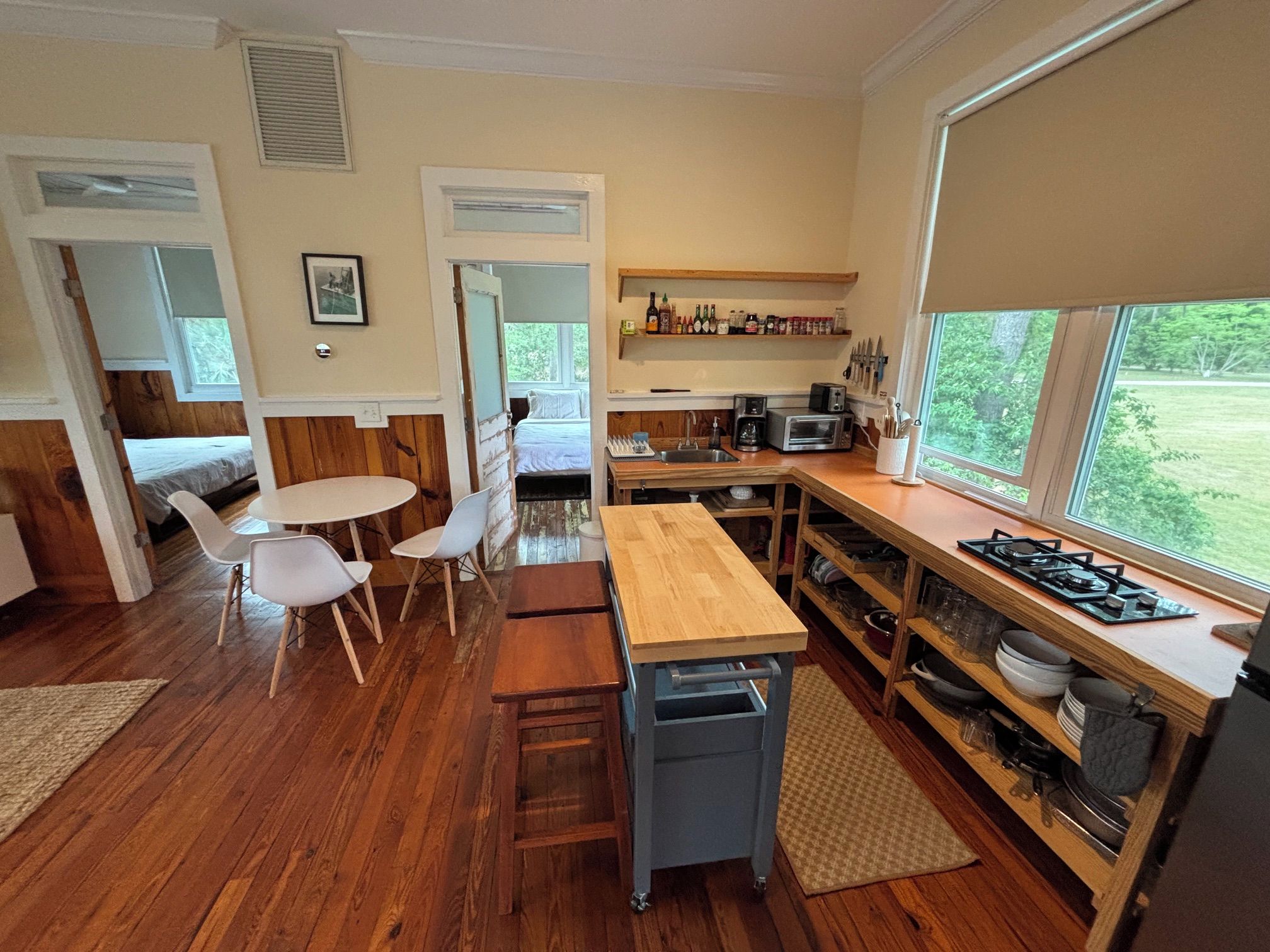 A compact kitchen with a dining area, wooden flooring, and a view of the outdoors.