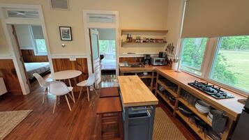 A compact kitchen with a dining area, wooden flooring, and a view of the outdoors.