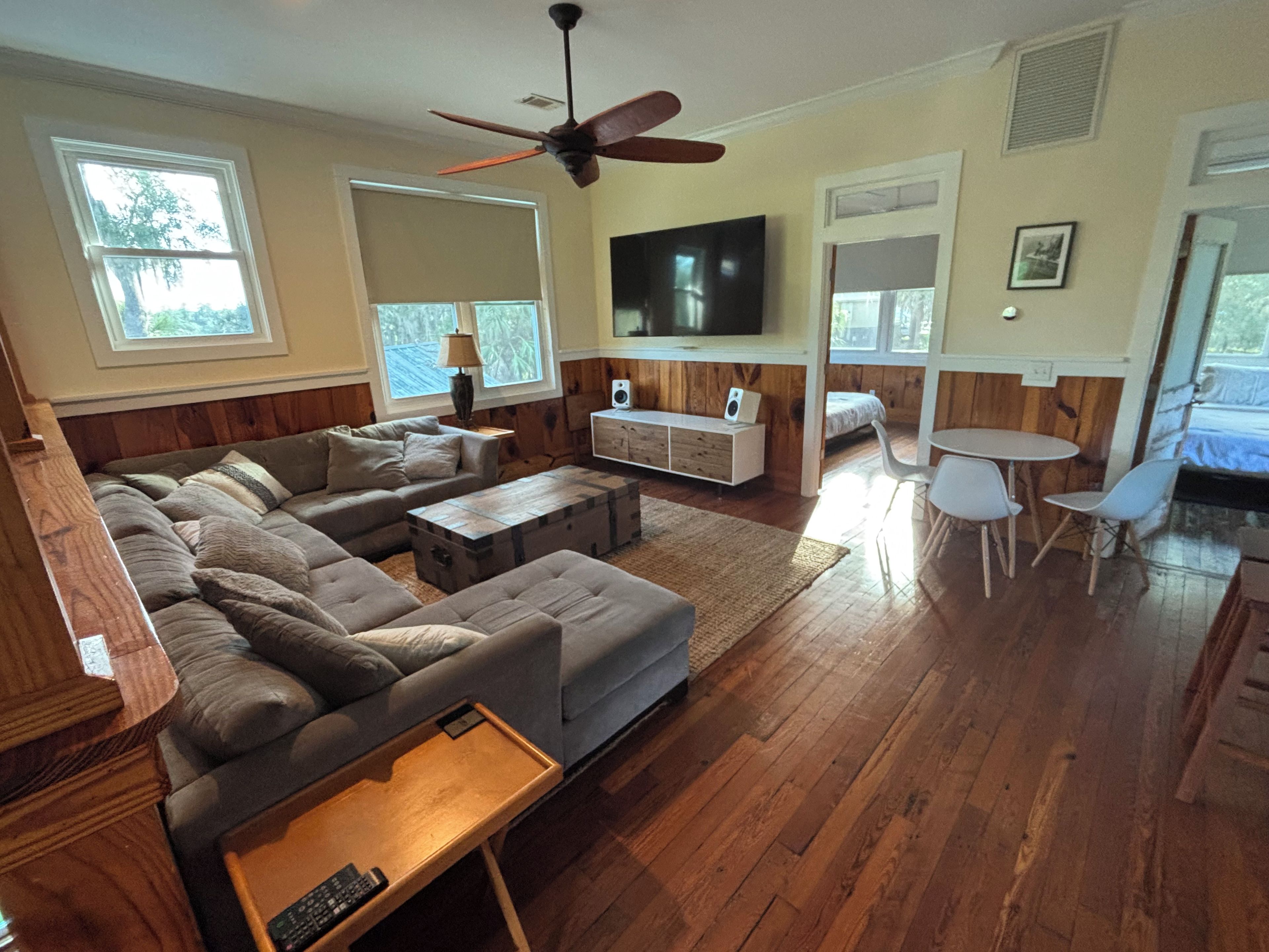 A spacious living room with a sectional sofa, a coffee table, a TV, and a dining area with a table and chairs.