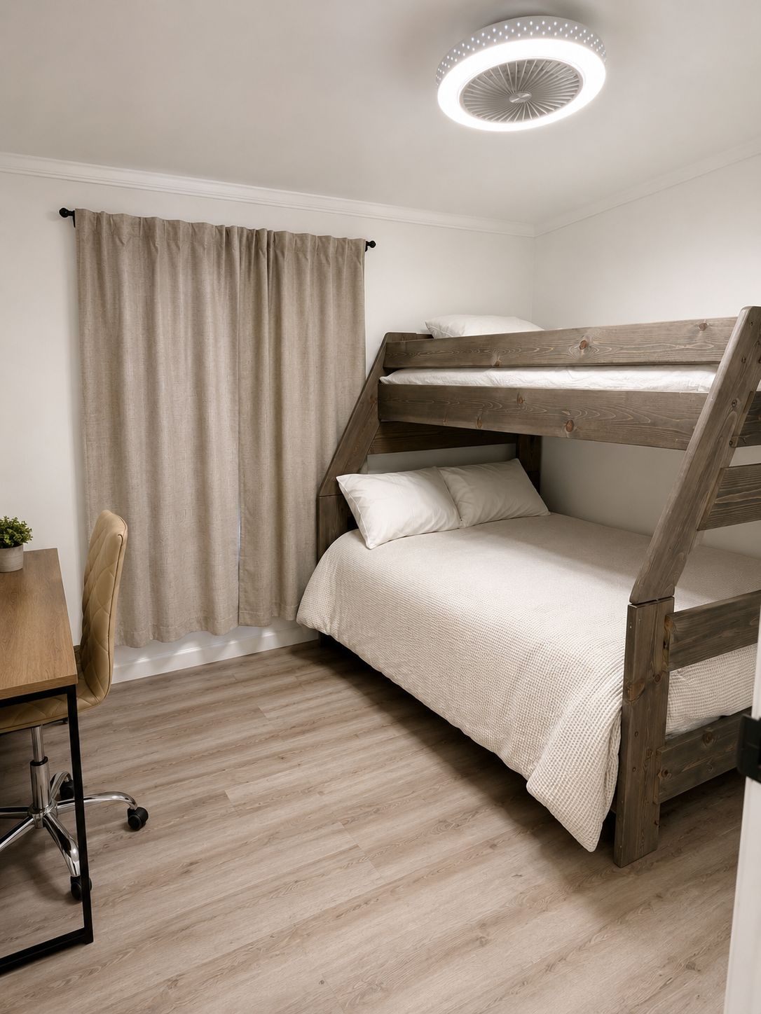 Uma cama beliche com estrutura de madeira, uma escrivaninha com cadeira e um lustre no teto.