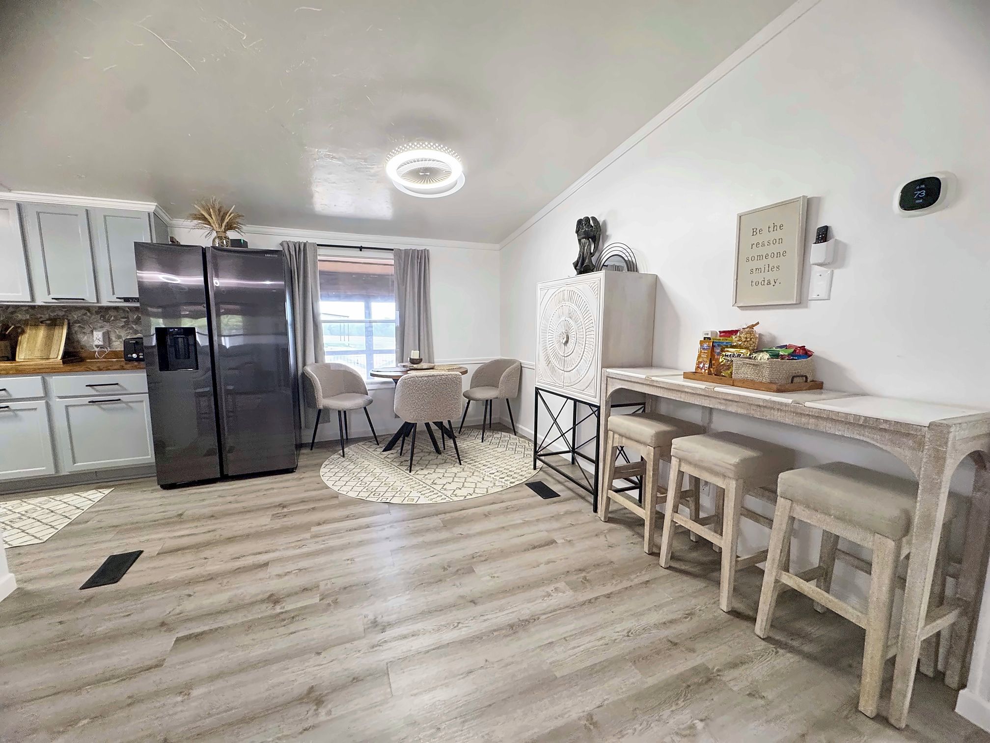 A modern kitchen with a refrigerator, stove, and dining area with chairs and a table.