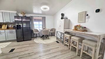 A modern kitchen with a refrigerator, stove, and dining area with chairs and a table.