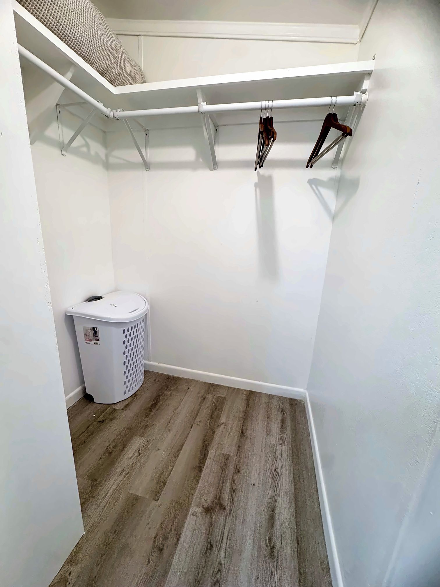 A laundry room with a white washing machine, a drying rack, and a wooden floor.