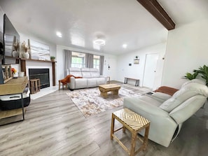 A spacious living room with a fireplace, a sofa, a coffee table, and a television.