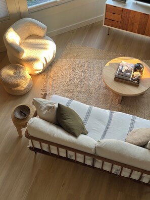 A modern living room with a sofa, a round coffee table, a side table, and a small wooden cabinet.