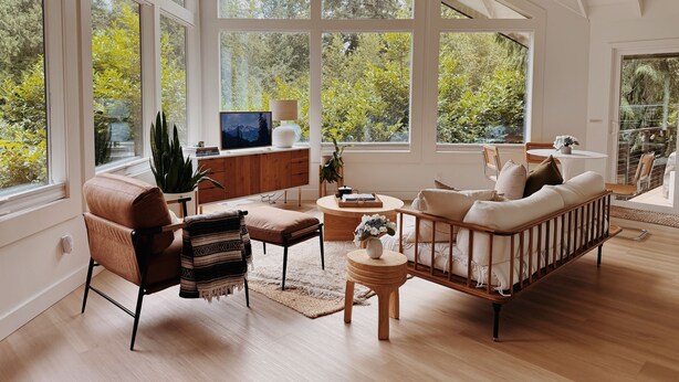 Un salon spacieux avec une grande fenêtre, des meubles en bois et une vue sur la verdure.