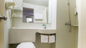 Ein Badezimmer mit Toilette, Waschbecken, Spiegel und Dusche.