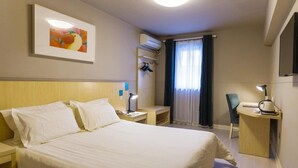 Una camera d'albergo con un letto, comodini, una scrivania, una sedia, un appendiabiti e un quadro appeso al muro.