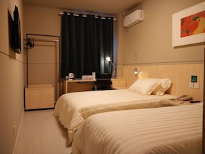 A hotel room with two beds, a desk, a chair, a coffee maker, an air conditioner, and a painting on the wall. - Jinjiang Inn Jiaxing Train Station (Jiaxing)