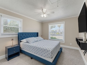 A bedroom with a bed, nightstand, ceiling fan, and two windows. - Saltwater & Bubbles 5 | Indian Rocks Beach (Indian Rocks Beach)