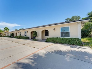 A row of single-story buildings with a flat roof, a paved driveway, and a well-maintained lawn. - Saltwater & Bubbles 5 | Indian Rocks Beach (Indian Rocks Beach)