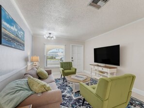 A living room with a sofa, two armchairs, a coffee table, a TV, and a painting on the wall. - Saltwater & Bubbles 4 | Indian Rocks Beach (Indian Rocks Beach)