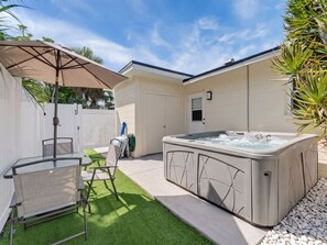A backyard with a hot tub, a covered patio table, and chairs. - Saltwater & Bubbles 4 | Indian Rocks Beach (Indian Rocks Beach)