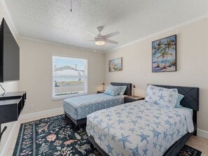 A bedroom with two beds, a ceiling fan, a window with blinds, and artwork on the walls. - Saltwater & Bubbles 4 | Indian Rocks Beach (Indian Rocks Beach)