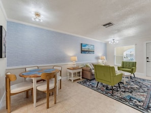 A living room with a dining table, chairs, a sofa, and a patterned rug. - Saltwater & Bubbles 4 | Indian Rocks Beach (Indian Rocks Beach)