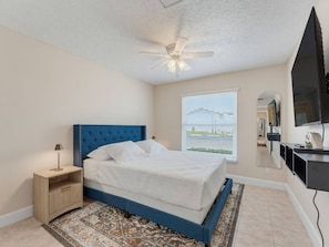 A bedroom with a bed, a nightstand, a ceiling fan, a window with blinds, and a flat-screen TV mounted on the wall. - Saltwater & Bubbles 1 | Indian Rocks Beach (Indian Rocks Beach)