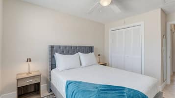 A bedroom with a bed, nightstands, a ceiling fan, a wardrobe, and a patterned rug.