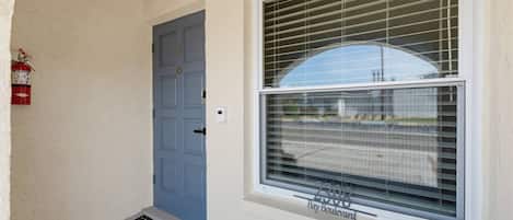 A blue door, a window with blinds, and a fire extinguisher on the wall.