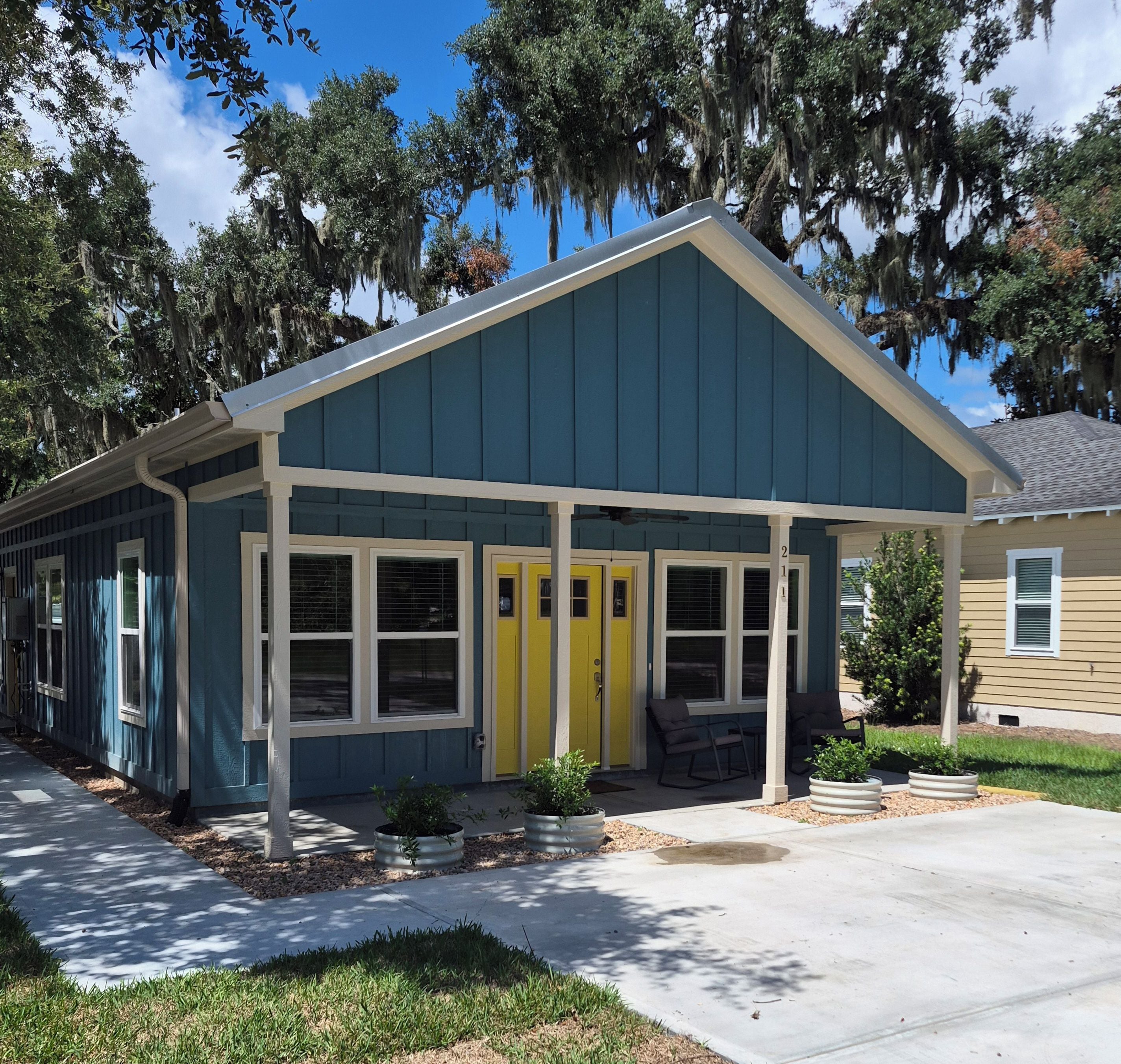 A two-story building with a blue exterior and a yellow front door.