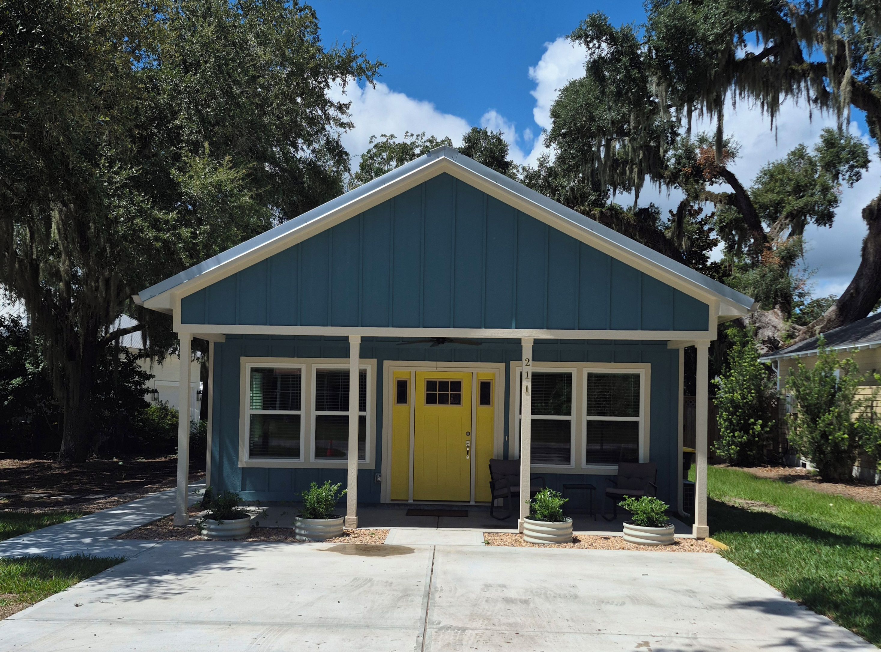 A single-story building with a yellow front door, white-framed windows, and a blue exterior.