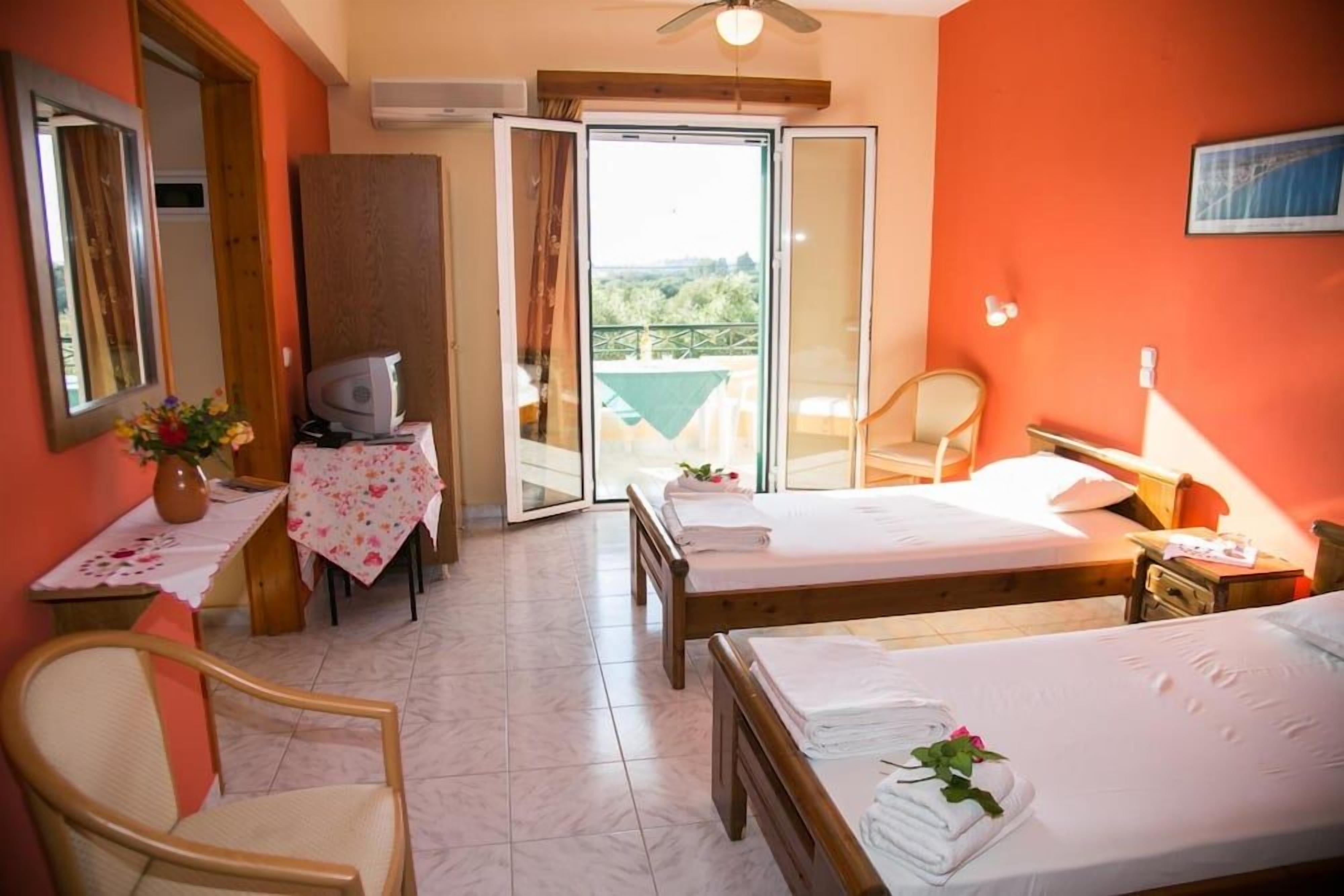 Een hotelkamer met twee bedden, een bureau met stoel, een televisie en een balkon met uitzicht.