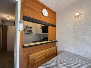 A kitchen with wooden cabinets, a microwave, and a clock on the wall. - Mountain View Apartment in Modane (Modane)