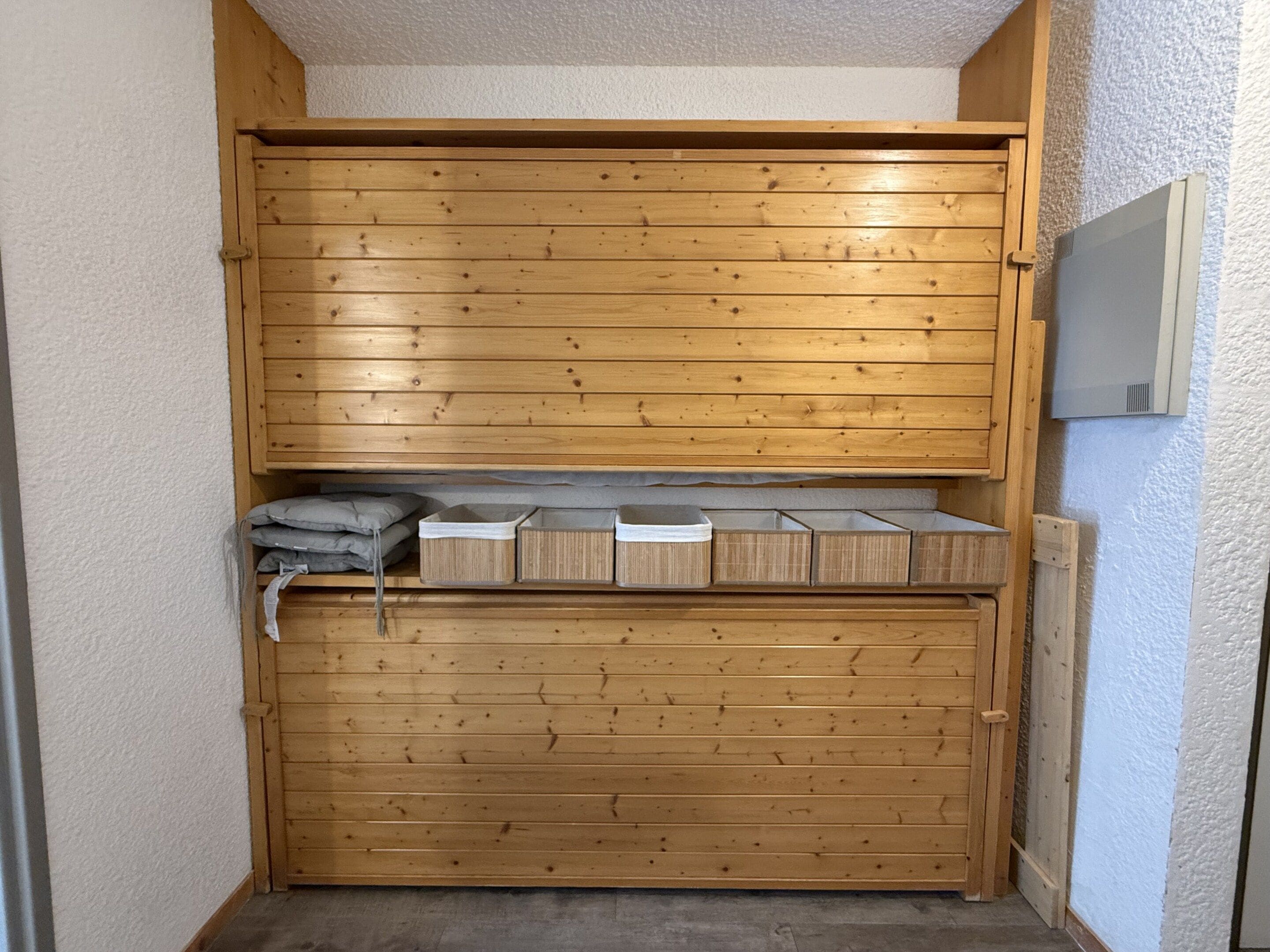 A wooden closet with multiple compartments, including shelves and drawers.
