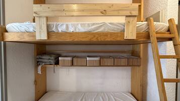 Una litera con estructura de madera, un estante inferior con cajas de almacenamiento y una escalera.