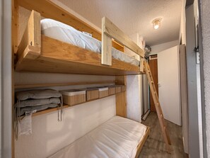 A bunk bed room with a ladder, a white wall, and a door. - Mountain View Apartment in Modane (Modane)