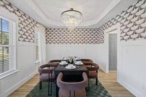 Ein Essbereich mit einer Chandelüster, einem für vier Personen gedeckten Tisch und strukturierter Wandtapete.
