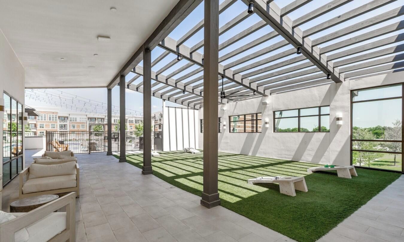 A spacious indoor area with a high ceiling, large windows, and a grassy area with seating.