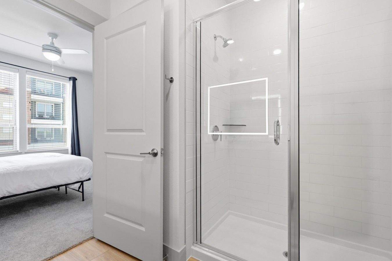 Un dormitorio con cama, puerta y zona de ducha con puerta de vidrio.