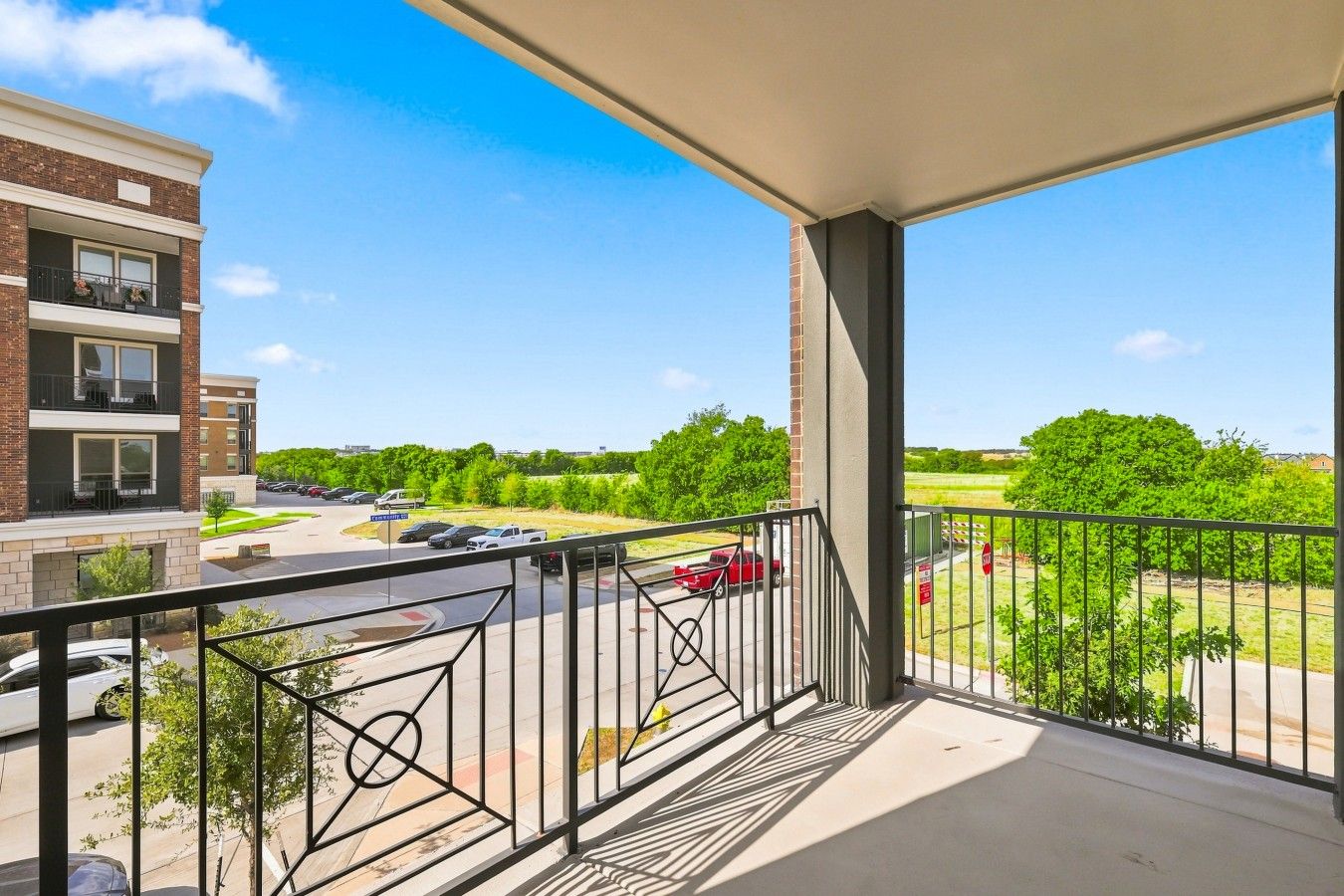 Un balcon donnant sur un parking et sur des espaces verts.