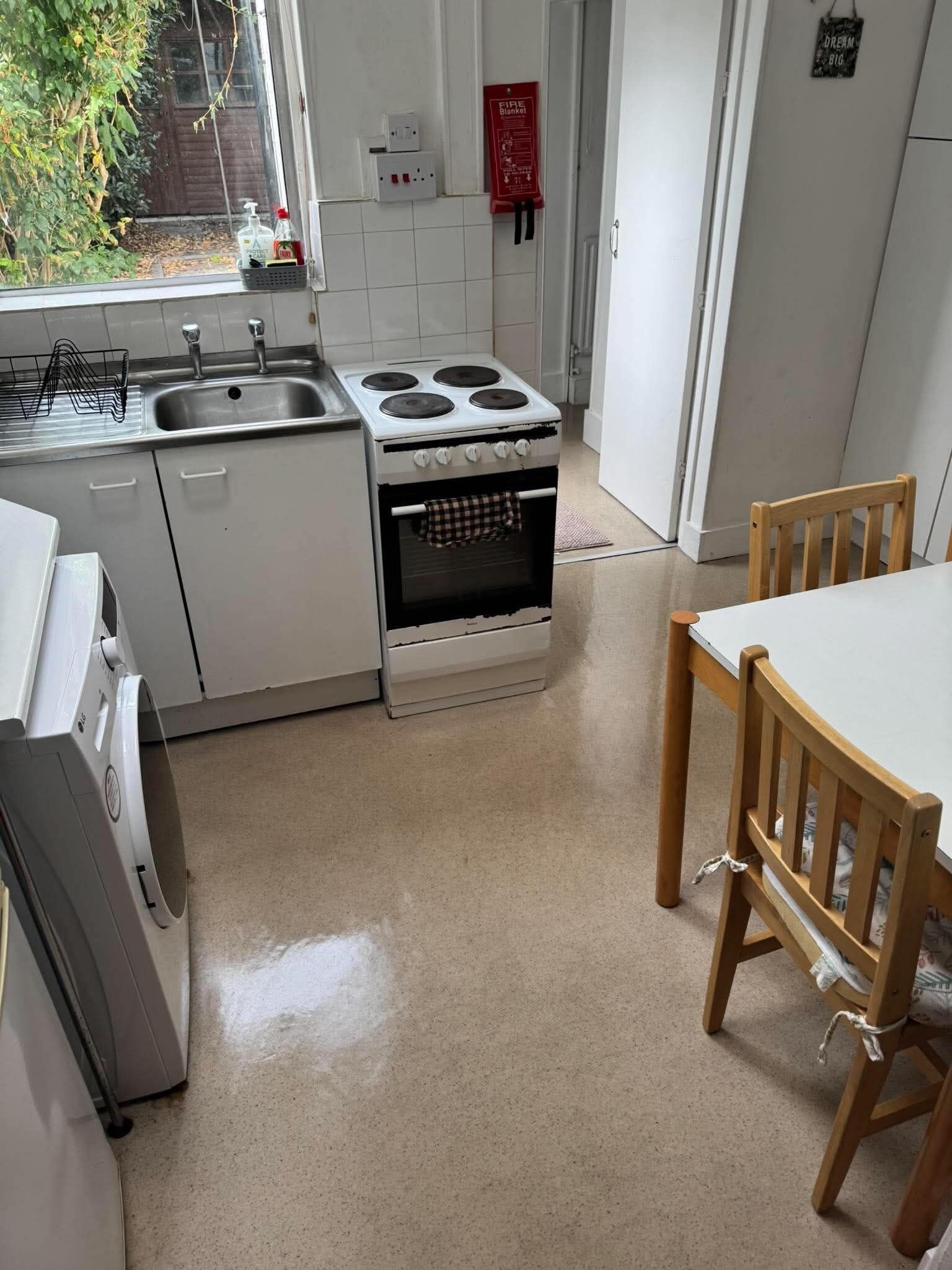 Une cuisine équipée d’une cuisinière, d’un évier et de chaises en bois.
