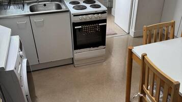 Une cuisine équipée d’une cuisinière, d’un évier et de chaises en bois.