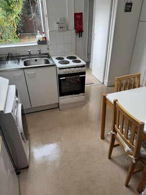 Une cuisine équipée d’une cuisinière, d’un évier et de chaises en bois.