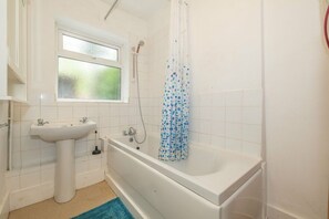 Ein Badezimmer mit einem weißen Waschbecken, einer Badewanne und einer Duschvorhang.