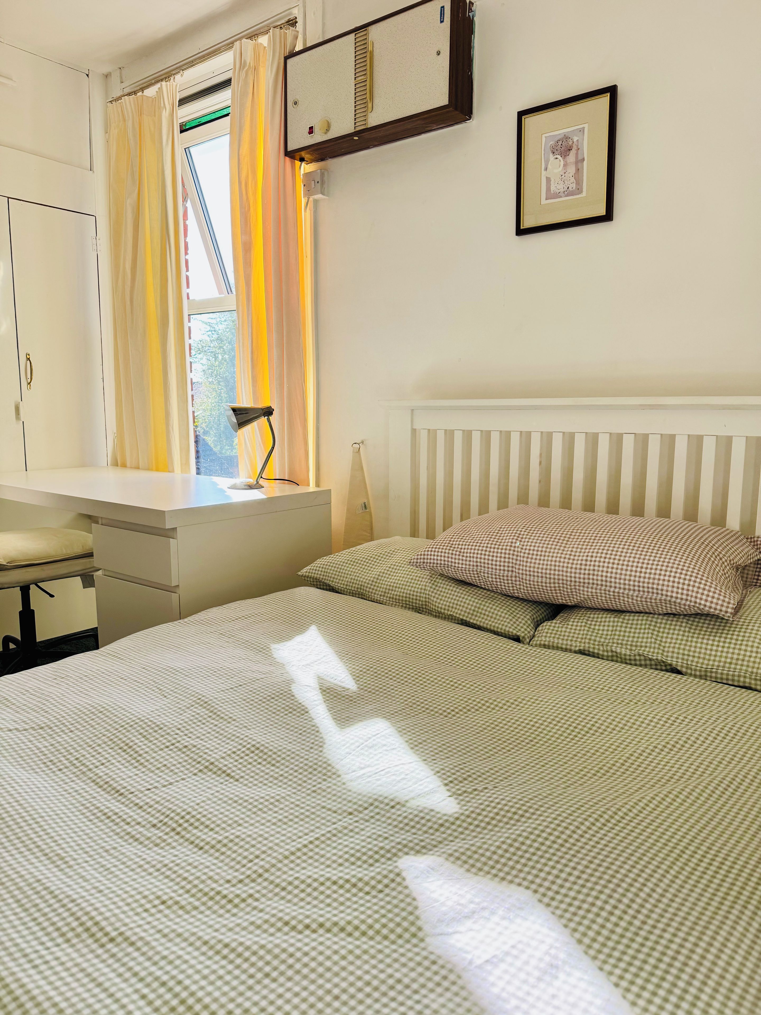 Une chambre à coucher avec un lit, un bureau et une fenêtre avec des rideaux.