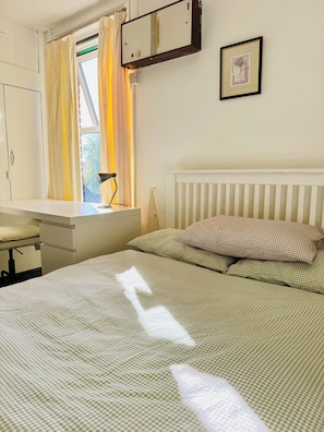 Une chambre à coucher avec un lit, un bureau et une fenêtre avec des rideaux.