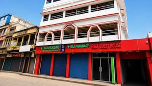 Um edifício com vários andares, com a sinalização da Raj Pharmacy e da Raj Guest House.