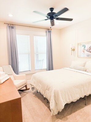 A bedroom with a bed, a chair, a desk, a ceiling fan, and a window with curtains. - Serene living- Masters Week rental! (Edgefield)