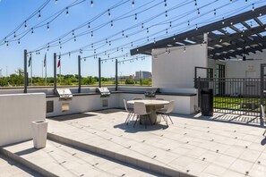 An outdoor patio with a grill, seating, and string lights. - Stylish 2B near Legacy West Wi-Fi, Fitness, Pool (Frisco)