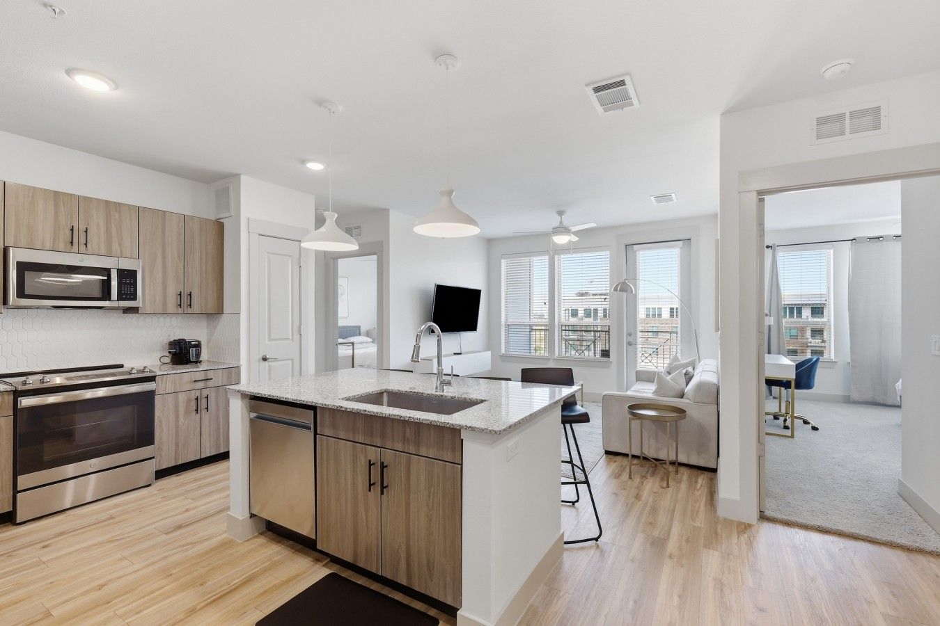 Una cocina moderna con armarios de madera, microondas integrado y una isla grande con pileta.