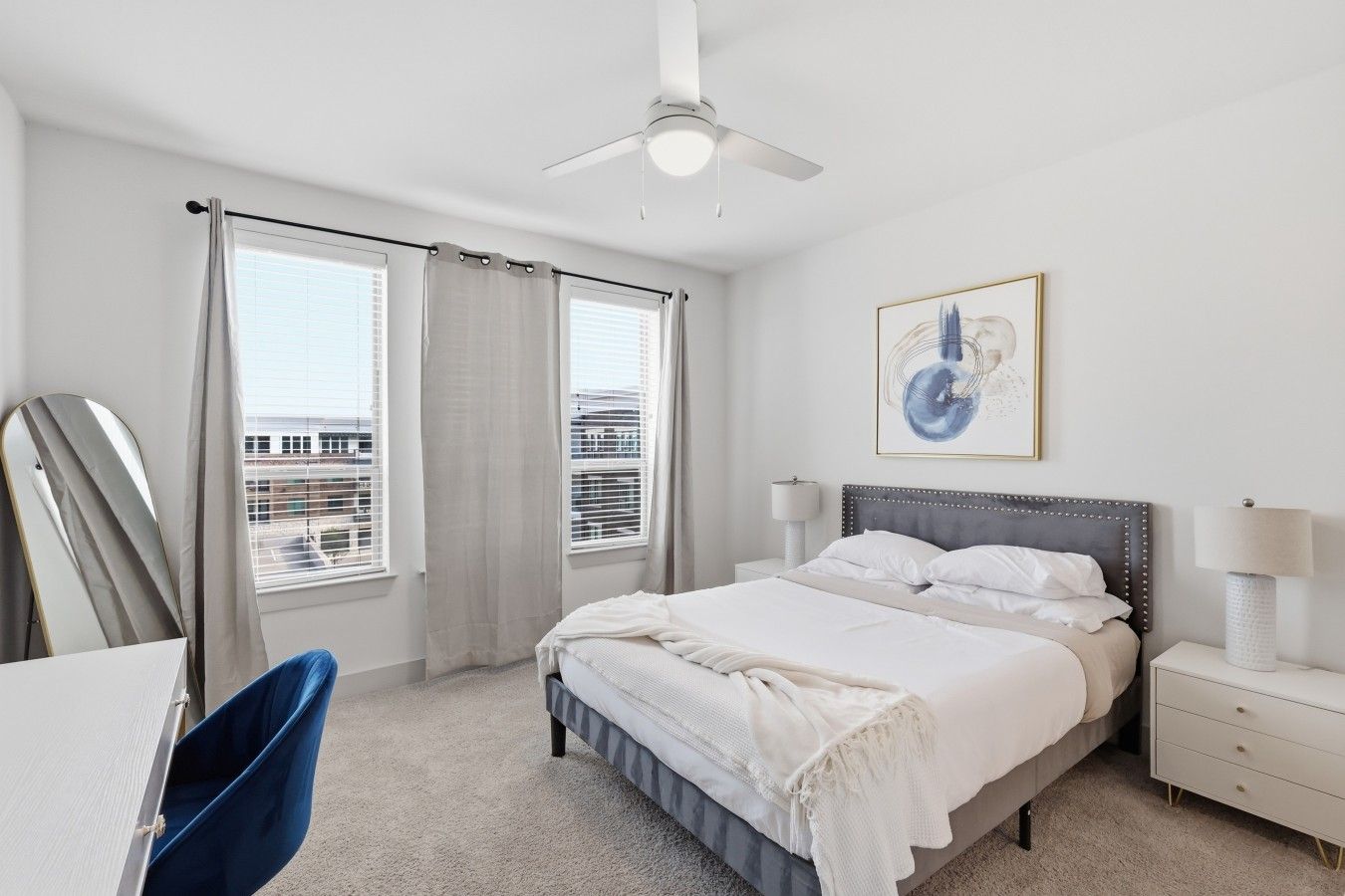 A hotel room with a bed, bedside tables, a ceiling fan, and a window with curtains.